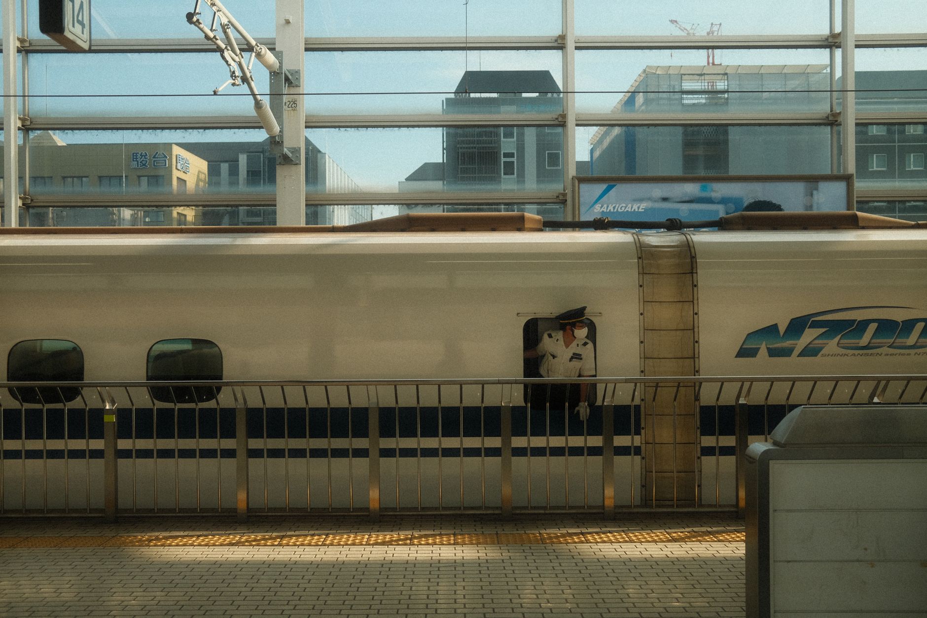 An N700 series Tokaido Shinkansen waiting at a Tokyo Station platform with a conductor beside it