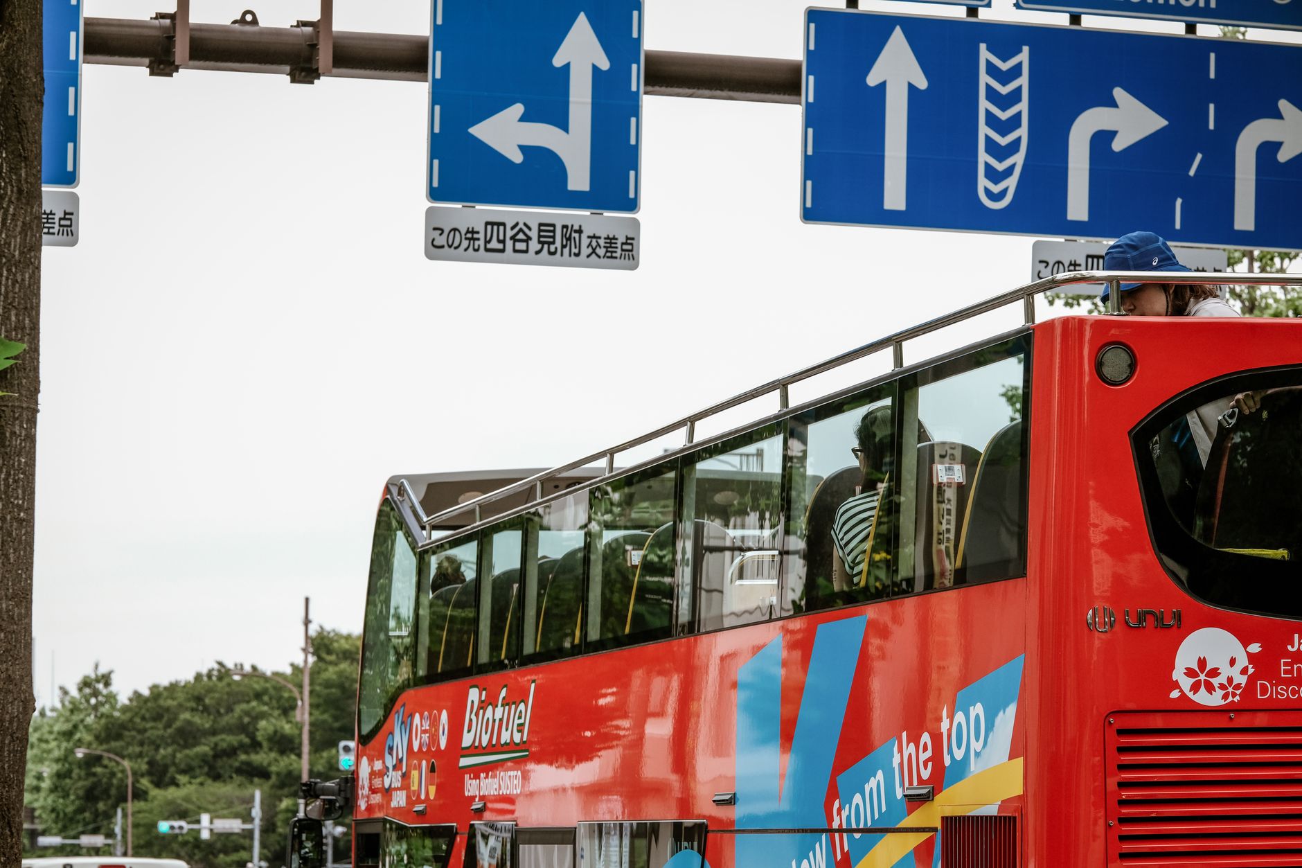 A red open-top double-decker sightseeing bus on a street in Tokyo